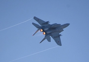 両翼からベイパーを引きながら飛ぶF-15